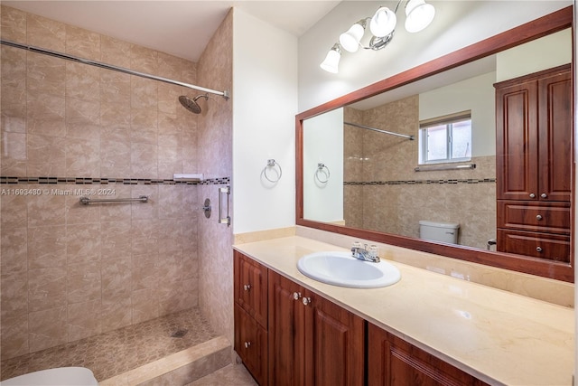 bathroom featuring a tile shower, vanity, and toilet