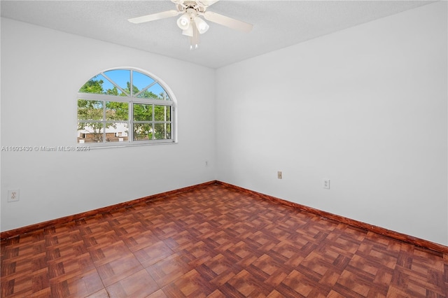 empty room featuring ceiling fan, dark parquet flooring, and a textured ceiling