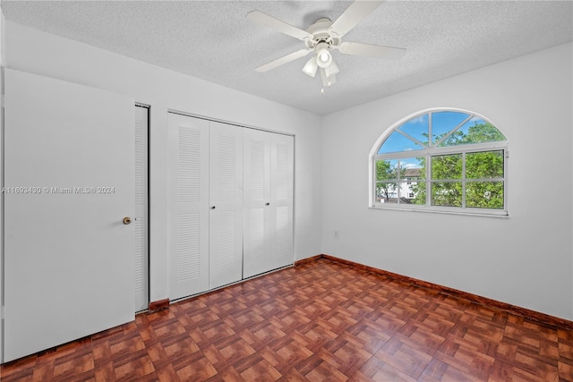 unfurnished bedroom with ceiling fan, dark parquet floors, and a textured ceiling