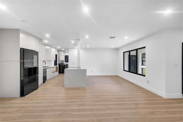 kitchen with dishwasher, backsplash, white cabinets, light wood-type flooring, and black fridge