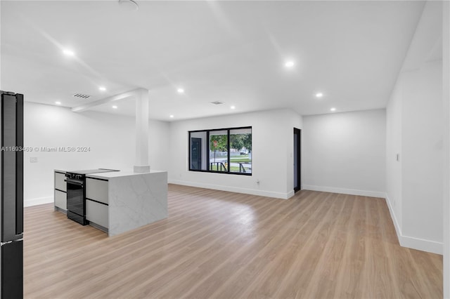 interior space featuring black appliances, light hardwood / wood-style flooring, and light stone countertops