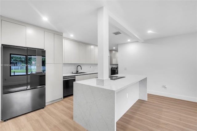 kitchen with sink, white cabinetry, black dishwasher, and stainless steel fridge