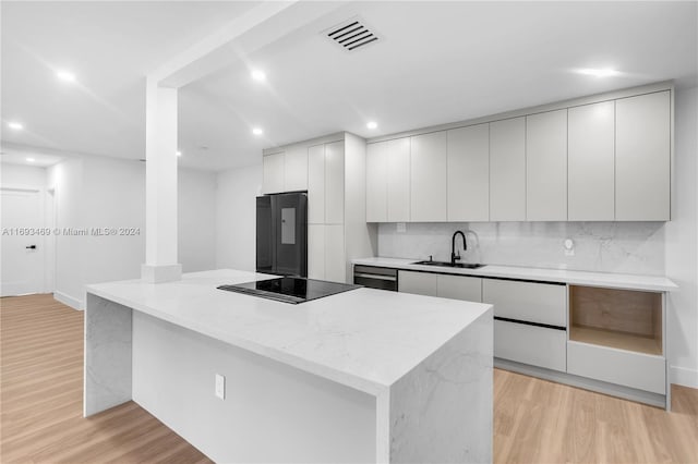 kitchen with fridge, sink, dishwashing machine, white cabinetry, and black electric cooktop