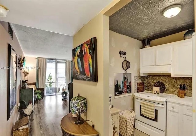 kitchen featuring tasteful backsplash, white cabinets, light wood-type flooring, and white electric range