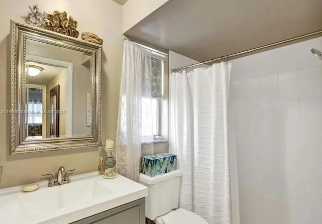 bathroom with vanity, curtained shower, toilet, and a wealth of natural light
