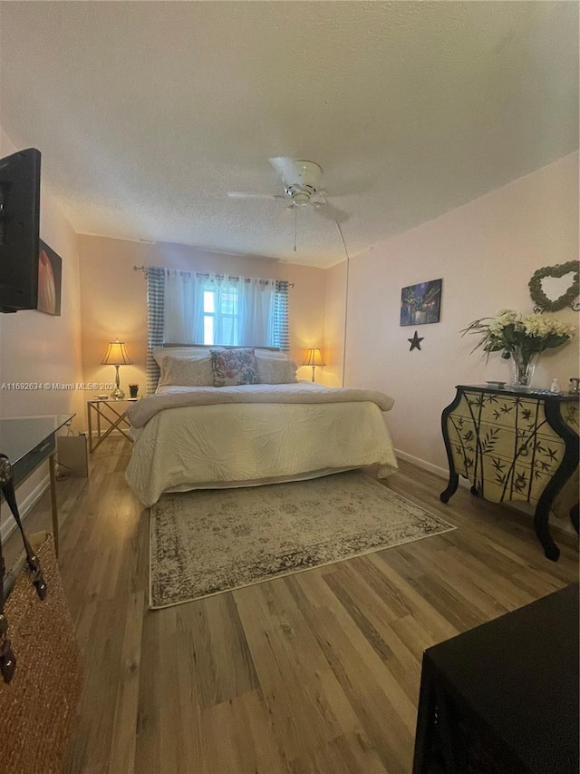 bedroom featuring hardwood / wood-style floors, ceiling fan, and a textured ceiling