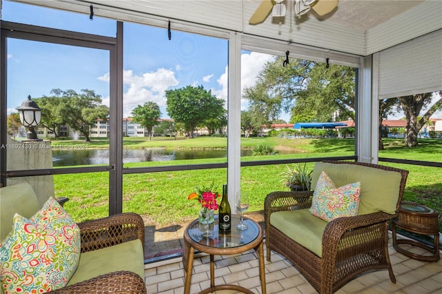 sunroom featuring ceiling fan and a water view