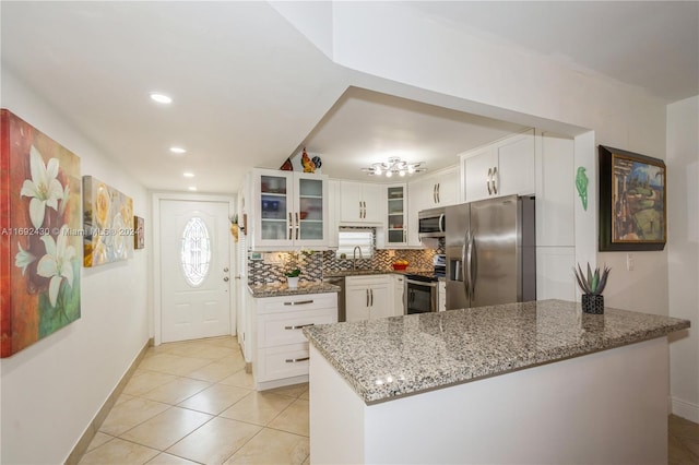 kitchen featuring white cabinets, light stone countertops, light tile patterned floors, kitchen peninsula, and stainless steel appliances