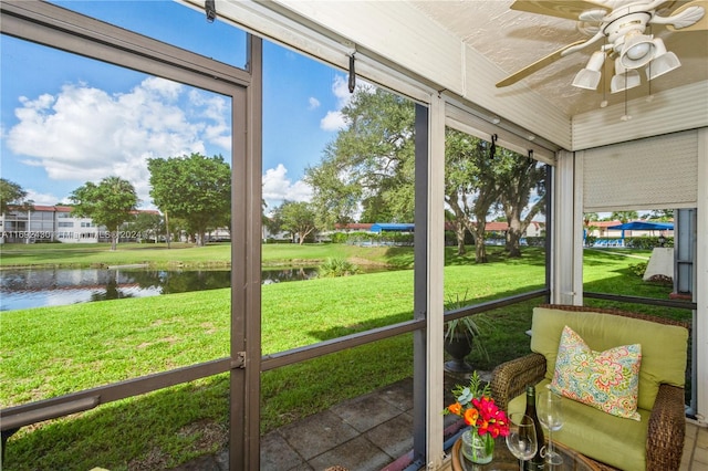 sunroom / solarium with a wealth of natural light, a water view, and ceiling fan