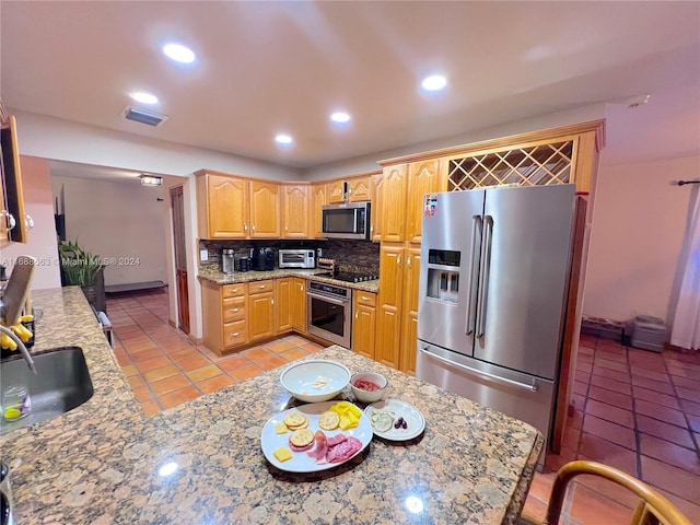 kitchen featuring tasteful backsplash, light tile patterned flooring, stainless steel appliances, light stone countertops, and sink