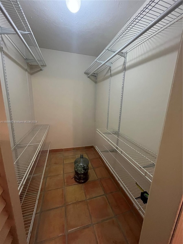 walk in closet with dark tile patterned flooring