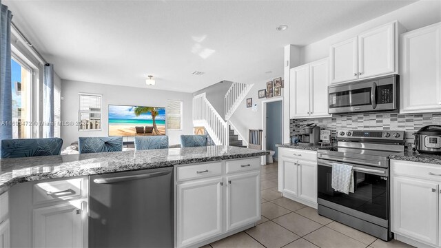 kitchen featuring light stone countertops, appliances with stainless steel finishes, and white cabinetry