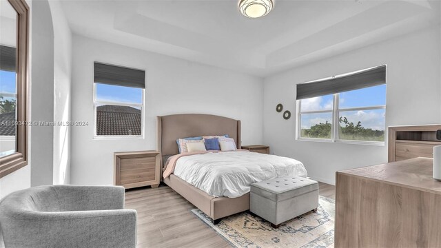 bedroom featuring a tray ceiling and light hardwood / wood-style flooring