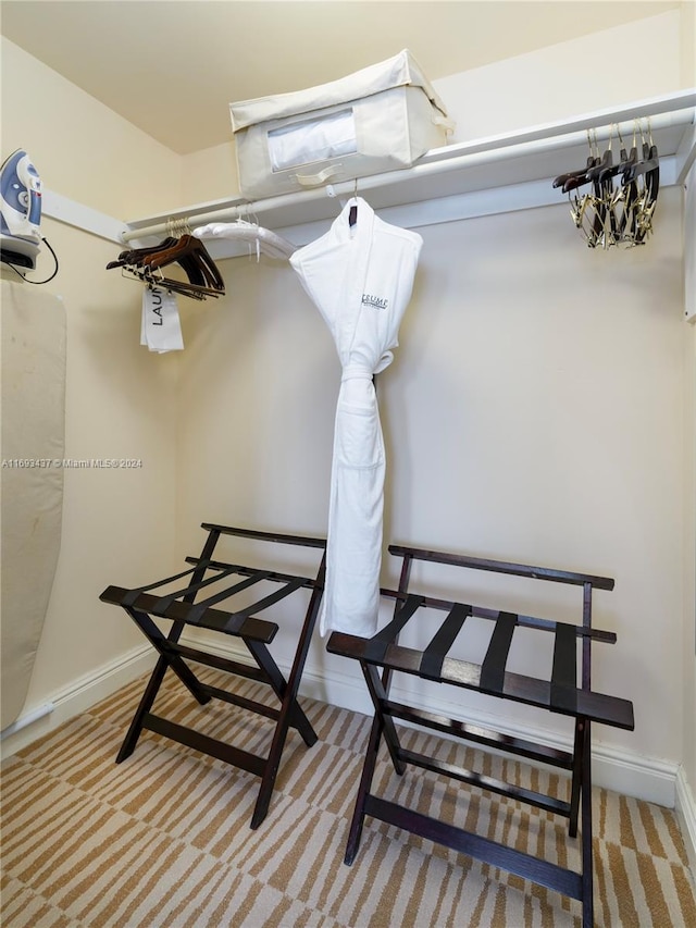 spacious closet featuring a chandelier and light colored carpet