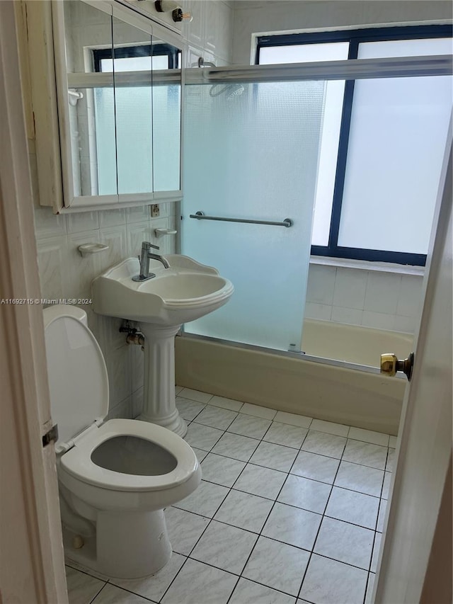 bathroom with tile patterned floors, toilet, shower / bath combination with glass door, and backsplash