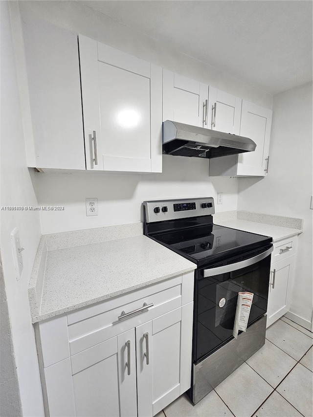 kitchen featuring white cabinets, light tile patterned floors, and black / electric stove