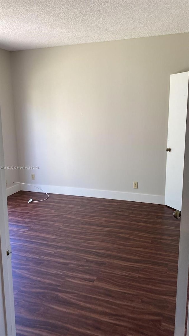 unfurnished room with dark wood-type flooring and a textured ceiling