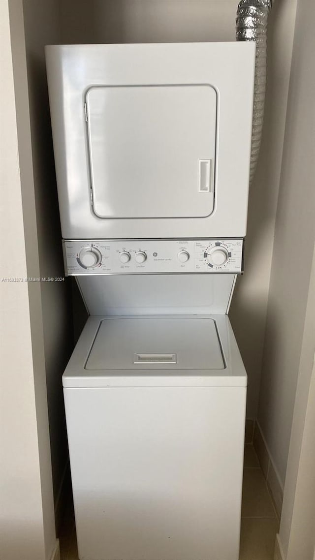 washroom with stacked washing maching and dryer and tile patterned flooring