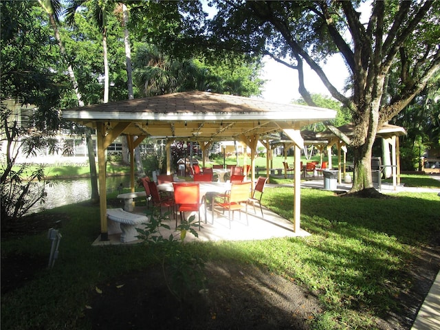 surrounding community featuring a gazebo, a water view, a patio, and a lawn