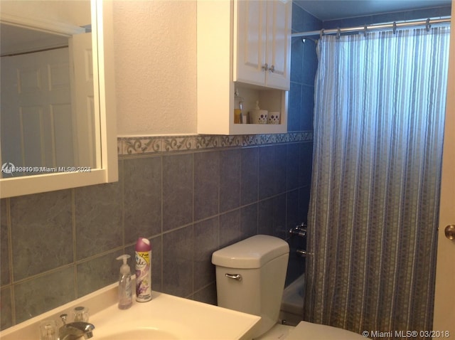 bathroom with toilet, a shower with curtain, tile walls, and sink