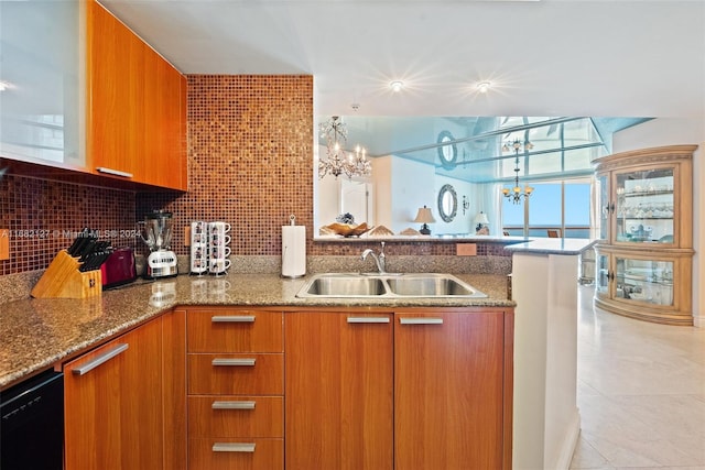 kitchen with sink, kitchen peninsula, backsplash, a chandelier, and stone counters