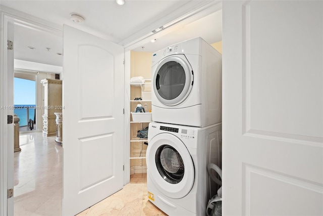 clothes washing area with stacked washing maching and dryer and a water view