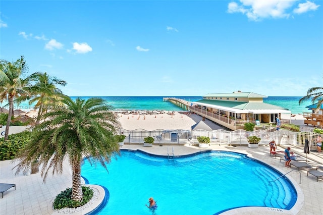 view of swimming pool featuring a water view and a view of the beach