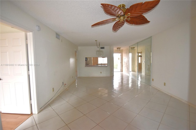 spare room featuring a textured ceiling, ceiling fan, and light tile patterned floors