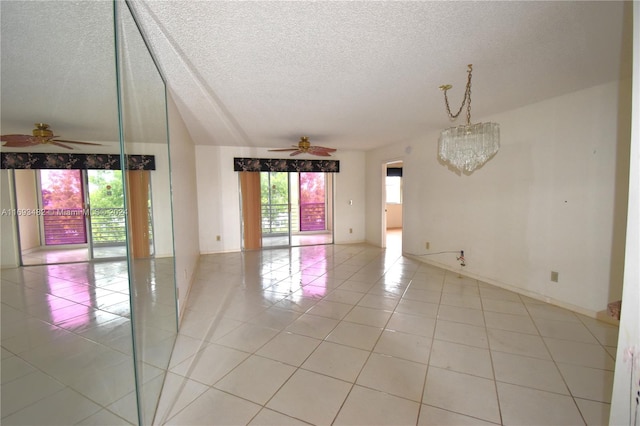 tiled spare room with ceiling fan with notable chandelier, a wealth of natural light, and a textured ceiling