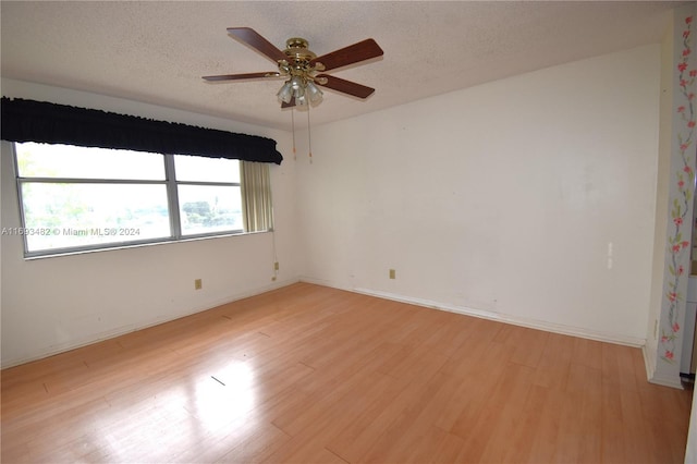 spare room featuring light wood-type flooring, a textured ceiling, and ceiling fan