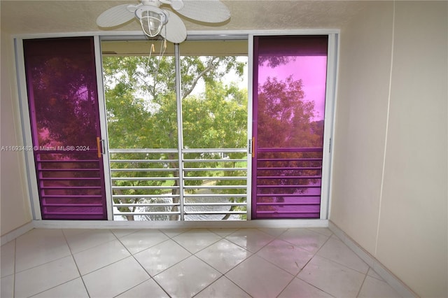 doorway featuring a textured ceiling, ceiling fan, and tile patterned floors