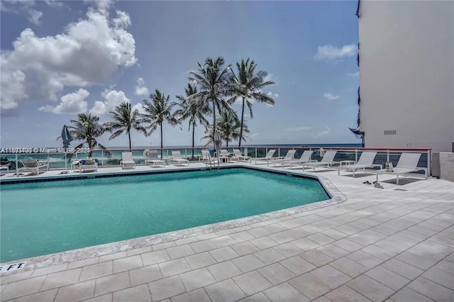 view of swimming pool with a patio and a water view