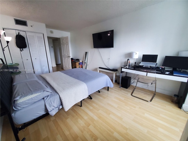 bedroom with light hardwood / wood-style flooring, a closet, and a textured ceiling