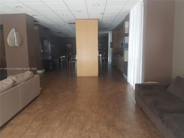 hallway with dark wood-type flooring and a drop ceiling