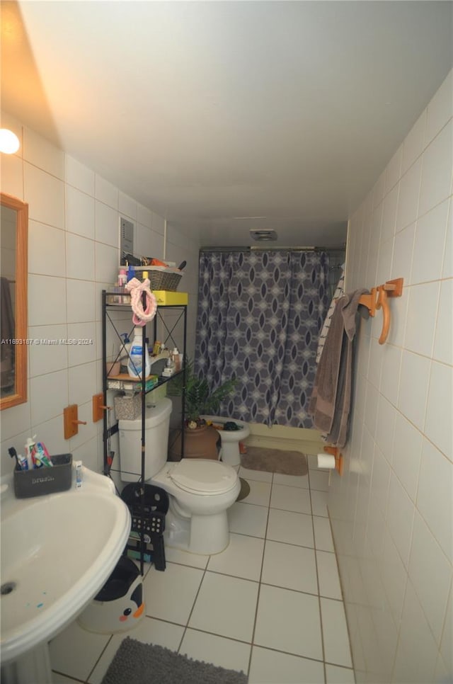 bathroom featuring sink, a shower with curtain, tile patterned floors, toilet, and tile walls