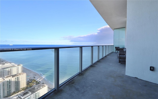 balcony with a water view and a view of the beach