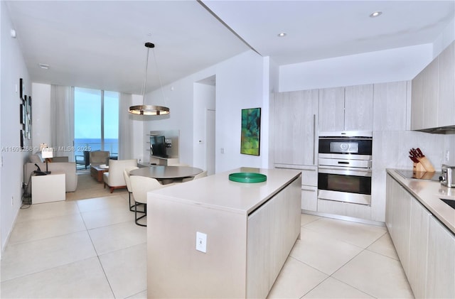 kitchen with light tile patterned floors, stainless steel double oven, light countertops, modern cabinets, and decorative light fixtures