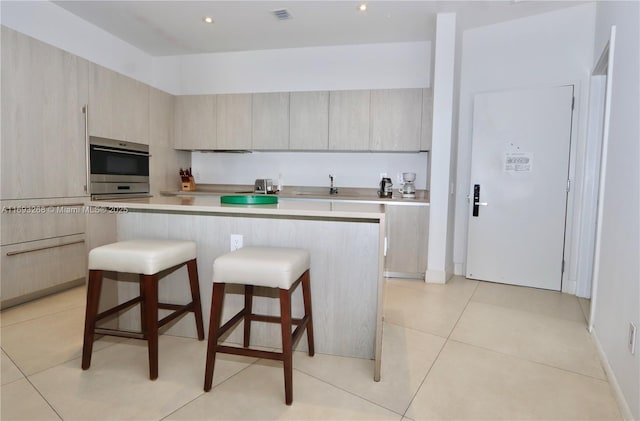 kitchen featuring light countertops, a kitchen island, visible vents, and light brown cabinetry