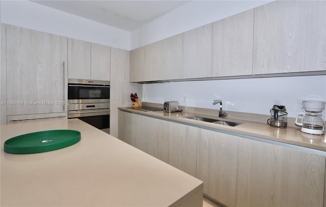 kitchen featuring light countertops, a sink, light brown cabinets, and modern cabinets