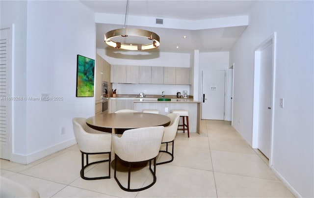 kitchen with a breakfast bar area, light countertops, hanging light fixtures, light tile patterned flooring, and modern cabinets