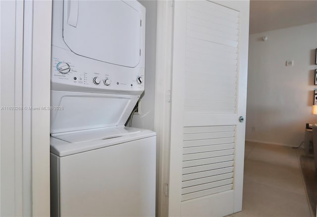 clothes washing area with tile patterned flooring, stacked washer and clothes dryer, and laundry area