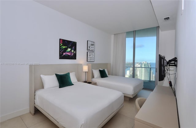 bedroom with a wall of windows, visible vents, baseboards, and light tile patterned floors