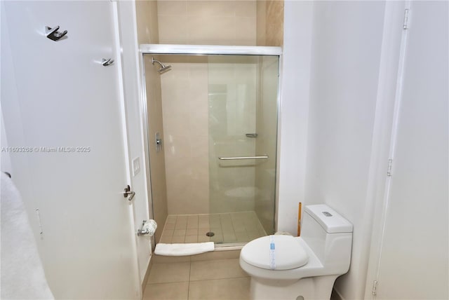 bathroom with tile patterned flooring, a shower stall, and toilet