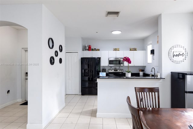 kitchen with appliances with stainless steel finishes, sink, white cabinetry, and light tile patterned flooring