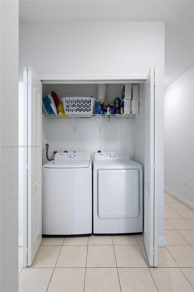 laundry room featuring washing machine and clothes dryer and light tile patterned floors