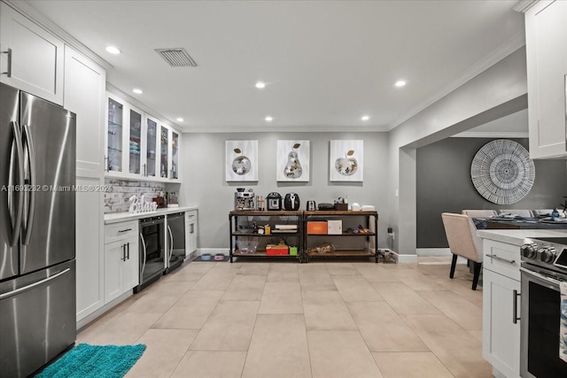 kitchen with stainless steel appliances, white cabinets, light tile patterned floors, and crown molding