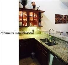 bar featuring decorative backsplash, sink, and light stone counters