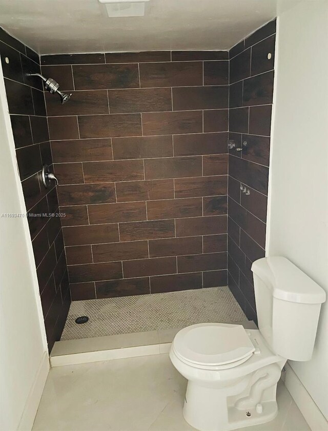 bathroom with toilet, tile patterned flooring, and tiled shower