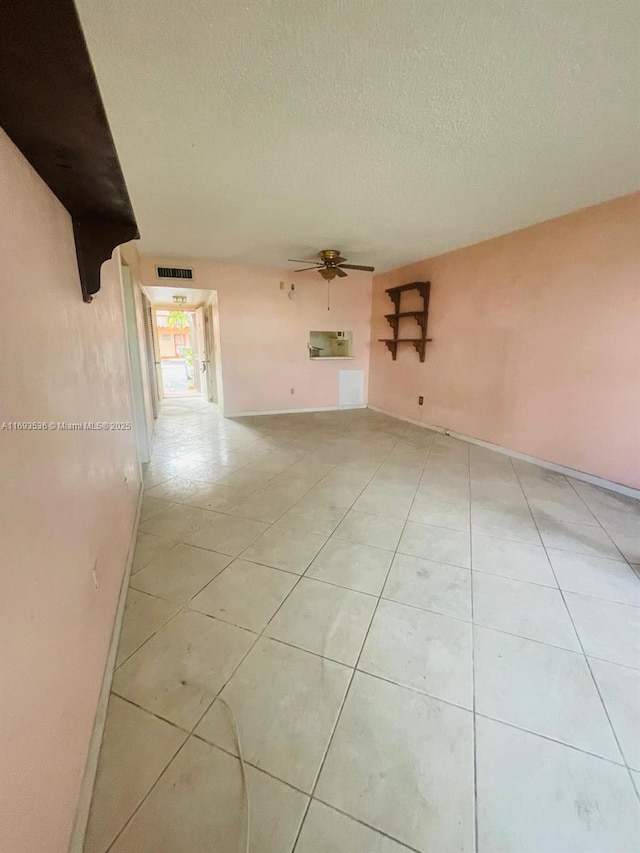 empty room featuring light tile patterned floors, ceiling fan, visible vents, and a textured ceiling