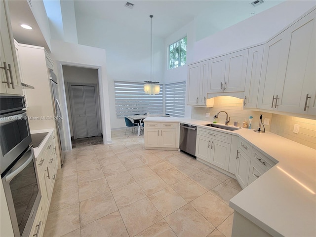 kitchen featuring tasteful backsplash, stainless steel appliances, hanging light fixtures, sink, and white cabinets